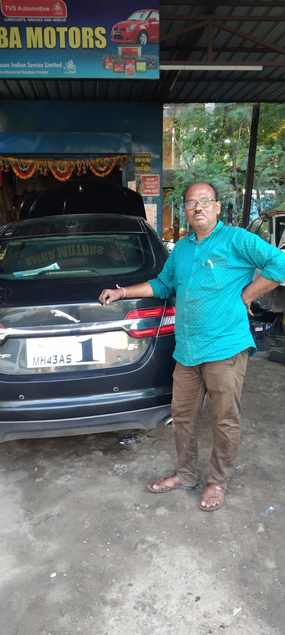 Pravin Kuntare, founder of Amba Motors, standing beside a serviced car